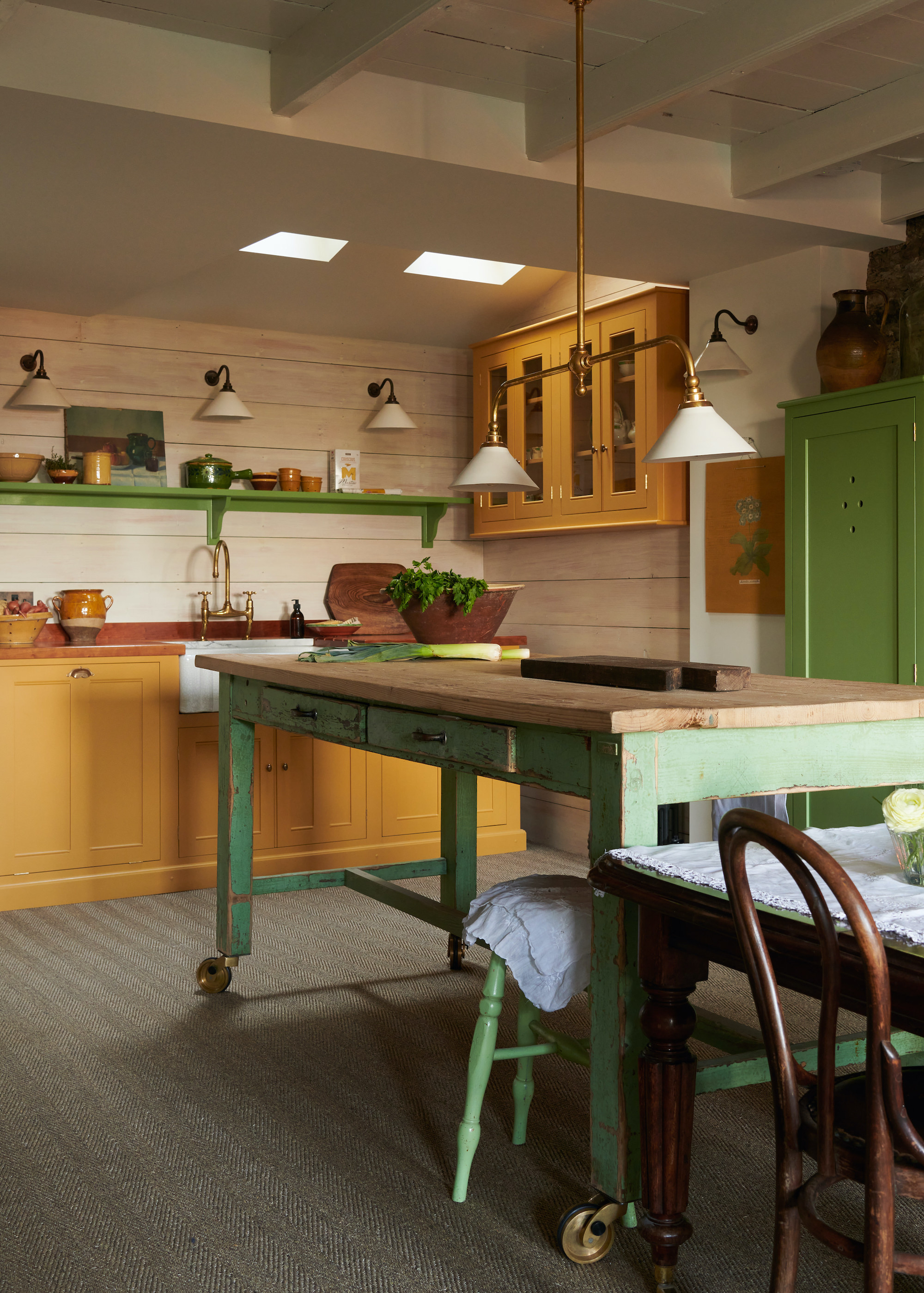 kitchen with prep trolley/ island on wheels. Above the portable island are pendant lights hanging. There is also a dining table next to the island.