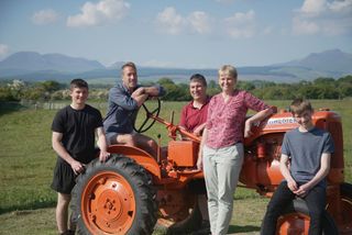 Ben Fogle with the Currie family standing by a tractor.