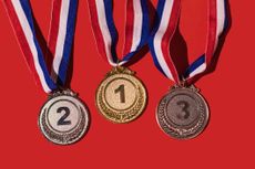 gold, silver and bronze medals lined up with red backdrop