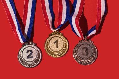 gold, silver and bronze medals lined up with red backdrop