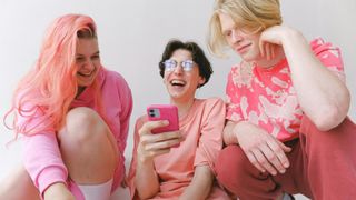 Three teenagers looking at phone and laughing