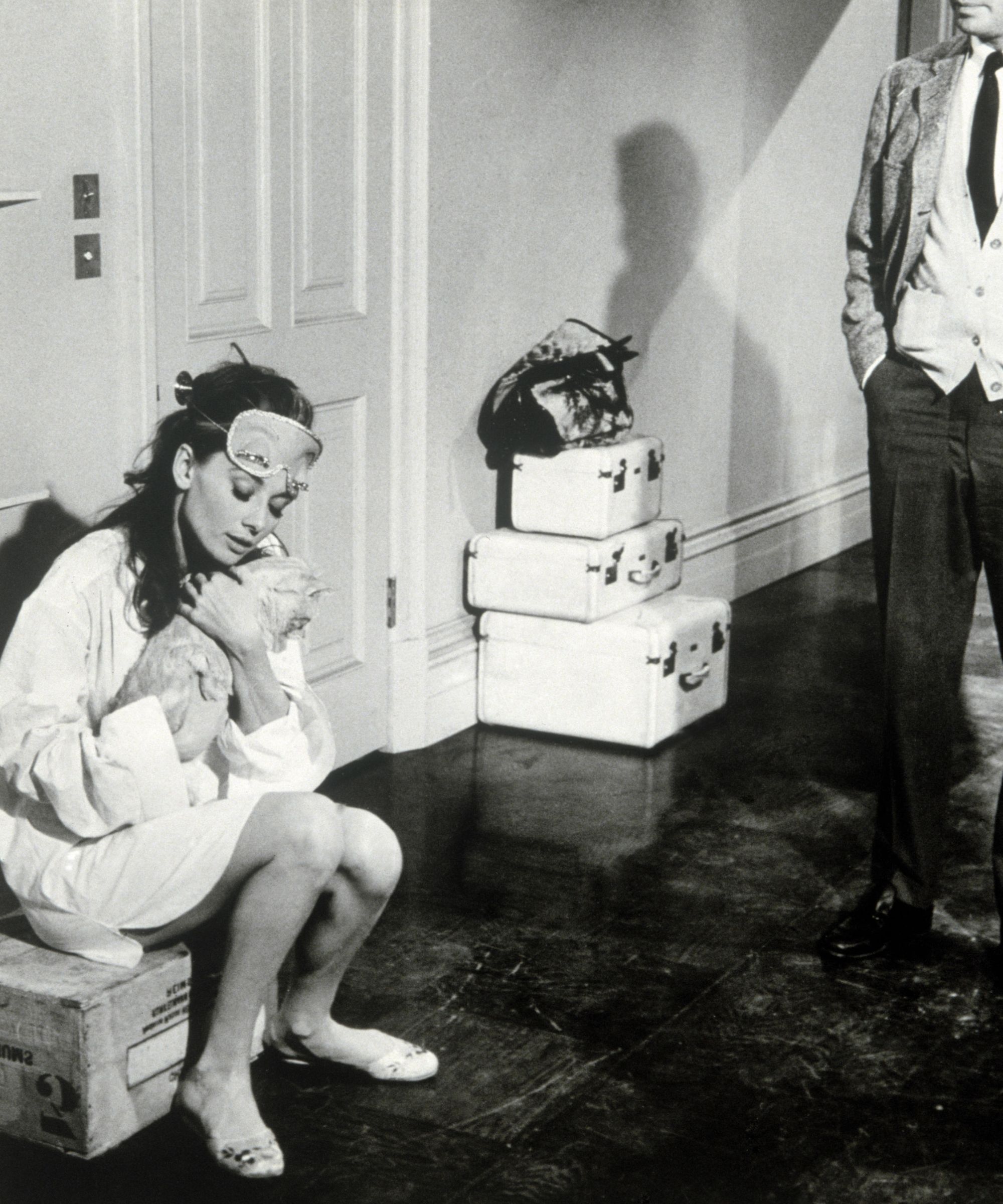 Audrey Hepburn in an apartment with stacks of suitcases