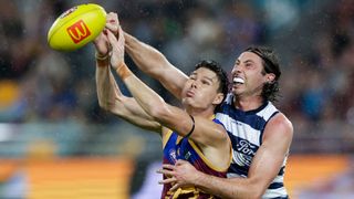  Eric Hipwood of the Lions (L), wearing a blue and maroon singlet, jumps for the ball with Jack Henry of the Cats, wearing a navy blue and white vest.