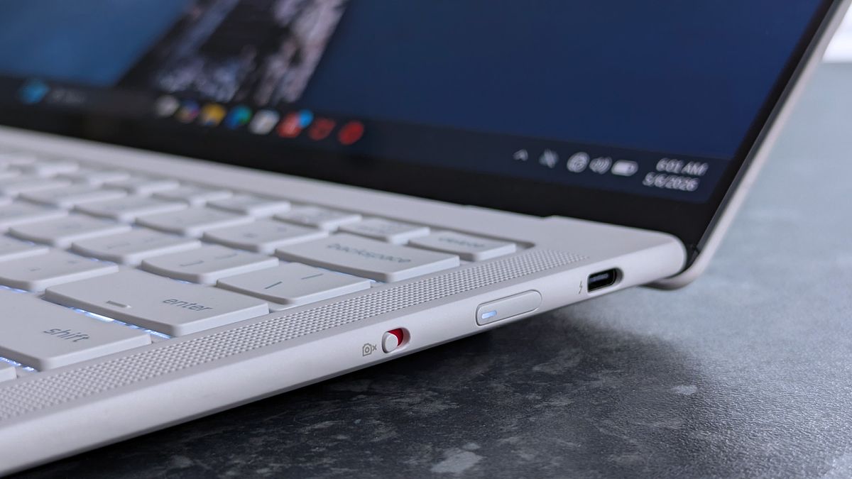 Close-up of a Lenovo Yoga Slim 7i Ultra (Gen 11) Aura Edition laptop with a focus on its side panel, showing a USB-C port and an accented webcam privacy switch. The screen displays app icons.
