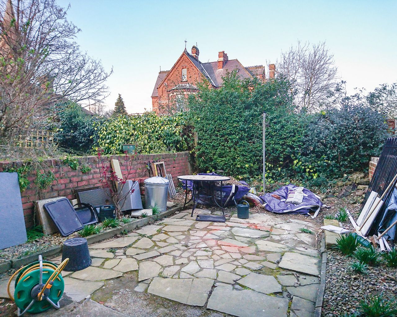 The before shot of a stone paved area in a small garden