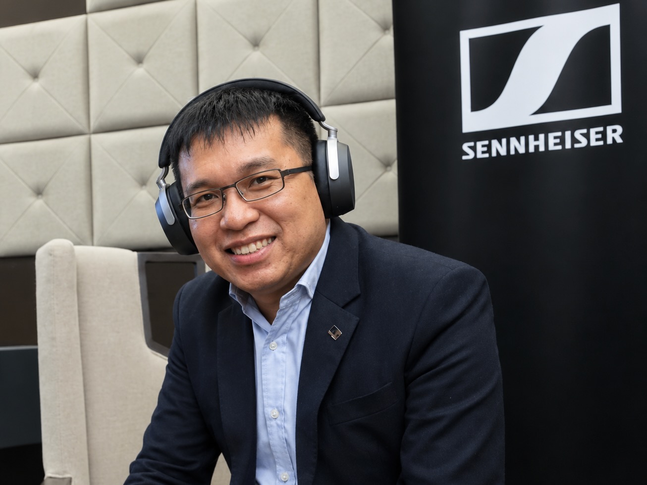 Wee Hong Kuan, Sennheiser's Senior Product Manager, wearing a pair of HDB 630 over-ear headphones in front of a Sennheiser logo.