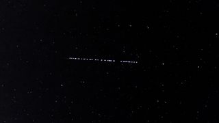 A Starlink satellite internet constellation operated by SpaceX streaks across the night sky.