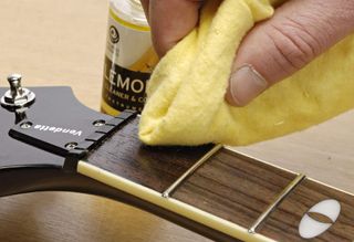Best guitar cleaning kits and tools: Man cleaning rosewood fingerboard with lemon oil