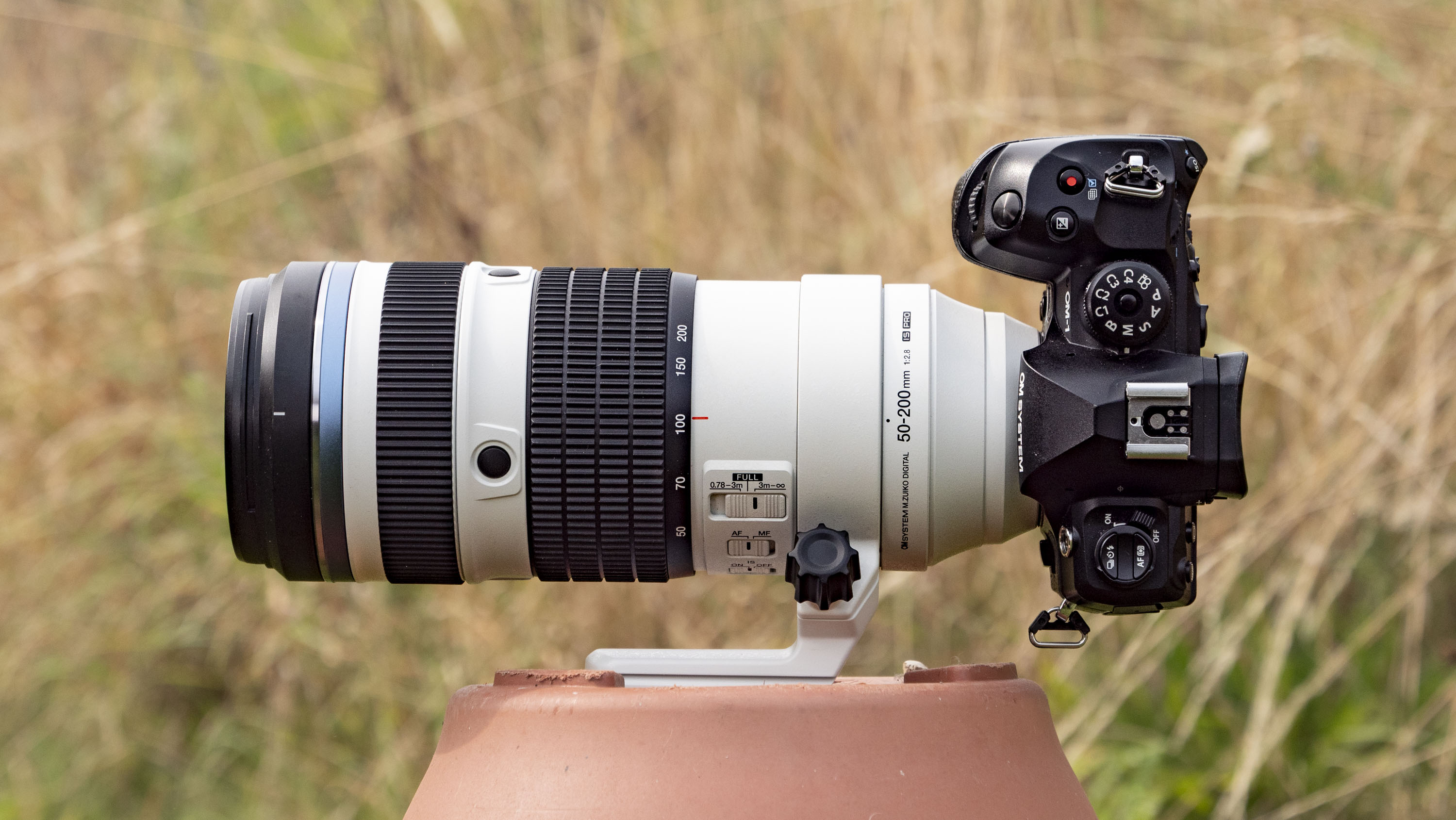 OM System M.Zuiko Digital ED 50-200mm F2.8 IS Pro lens attached to an OM-1 II, outdoors with long grass in the background