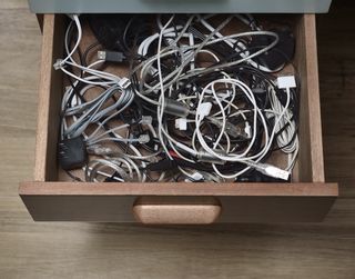 Desk drawer filled with cables, wires and plugs