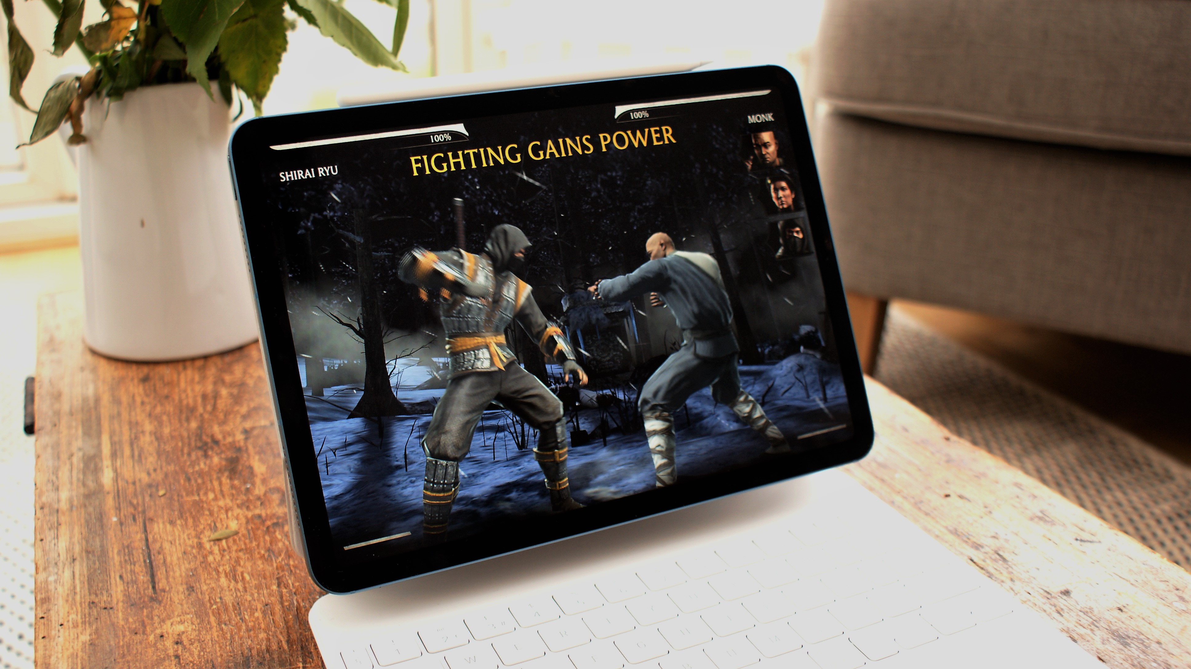 En iPad Air 2022 står på ett bord i ett vardagsrum och kör ett fighting-spel.