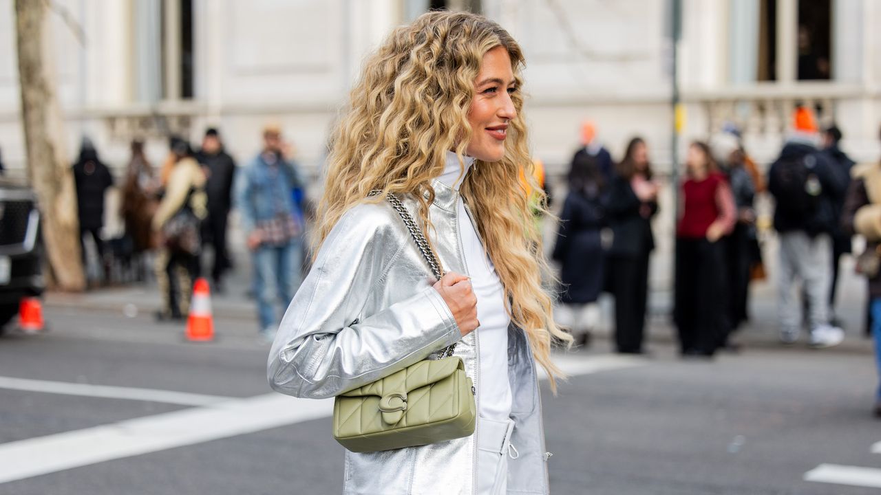 Best hair products for frizz - Emili Sindlev wears silver jacket, pants with NY print, turtleneck, green bag - gettyimages 2007516071