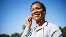 Woman putting headphone into ears in sunshine
