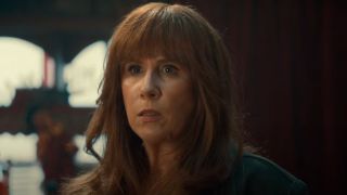 Catherine Tate looks worried while standing in front of a red curtain in Doctor Who.