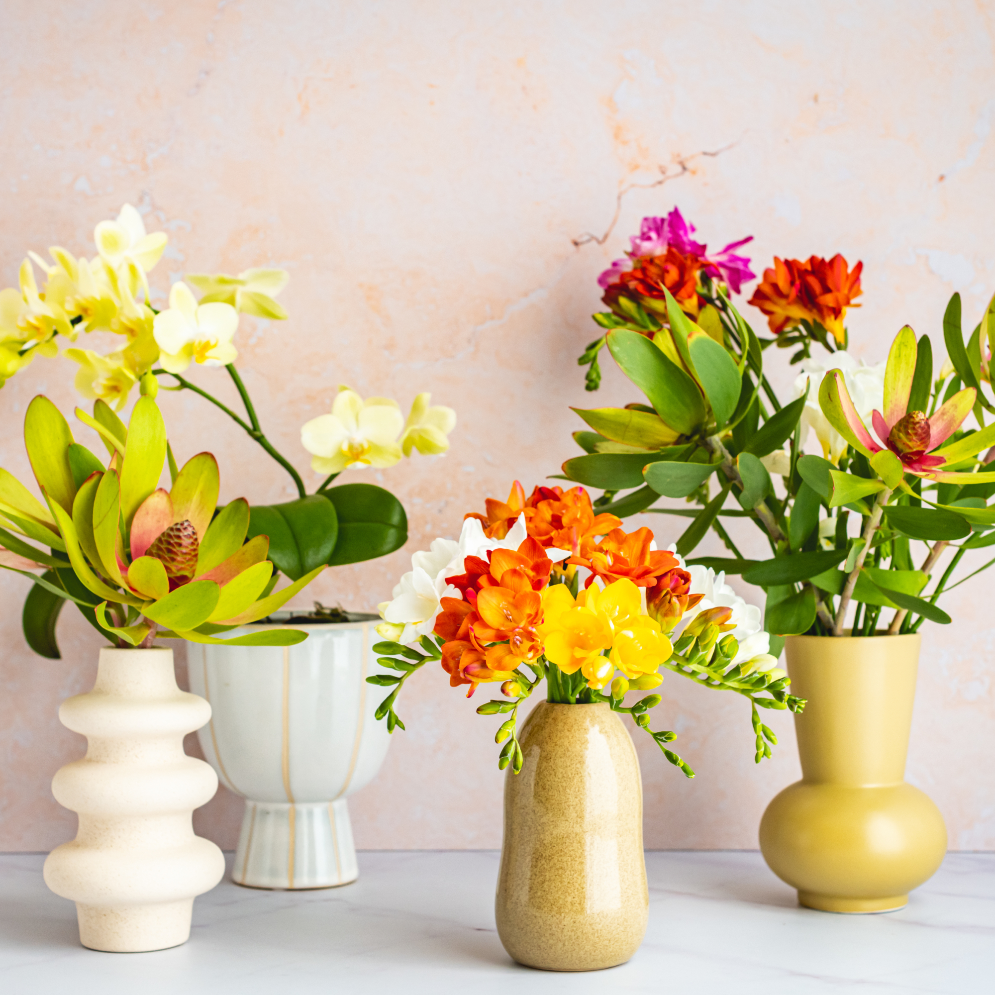 assortment of vases with unique flower arrangements on a marble table
