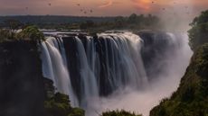 Victoria Falls in Zambia at sunset with birds flying around it