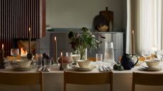 Fall table setting with white tablecloth, white crockery and grape and artichoke-shaped serving bowls