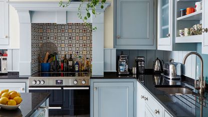 kitchen with pale blue cabinets and black worktops with kitchen appliances on display