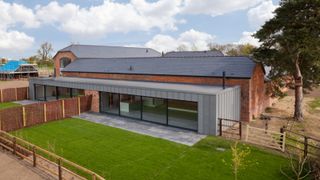 barn conversion with modern zinc clad flat roof extension on front