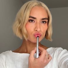 An image of a woman applying makeup while taking a selfie.