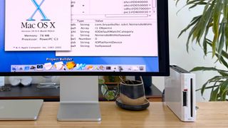 Close up of Nintendo Wii on desk connected to monitor with Mac OS X on screen.