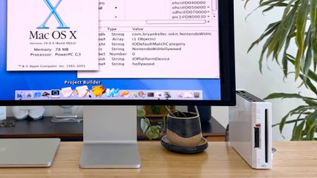 Close up of Nintendo Wii on desk connected to monitor with Mac OS X on screen.