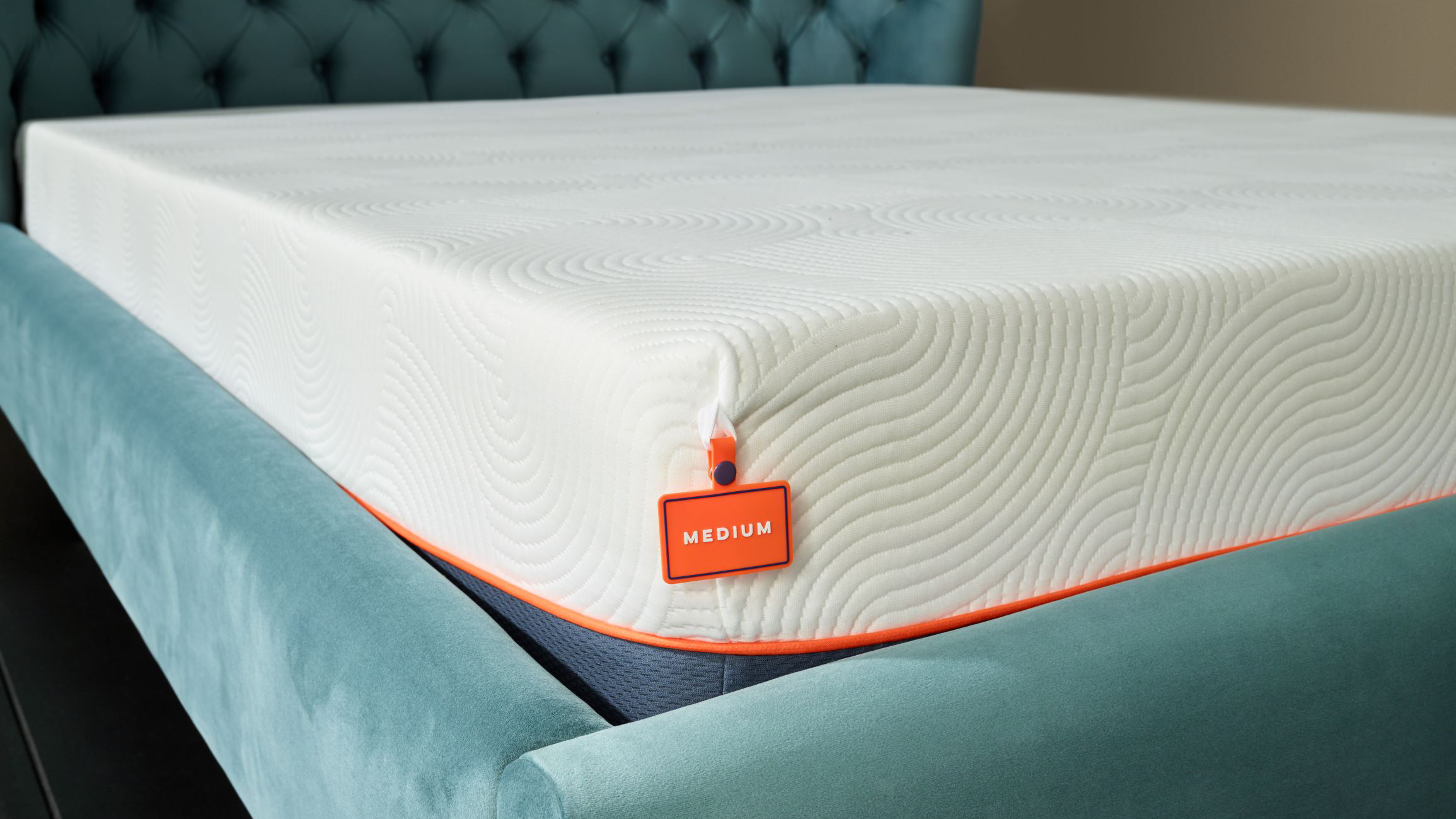 Image shows the bottom left hand corner of the Brook + Wilde Lux Mattress with its white top and navy blue base