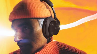 Bang & Olufsen Beoplay H95 review: man dressed in orange with headphones on
