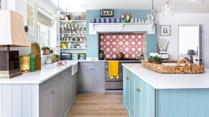 Kitchen with blue island and grey cabinetry and pink patterned tile splashback
