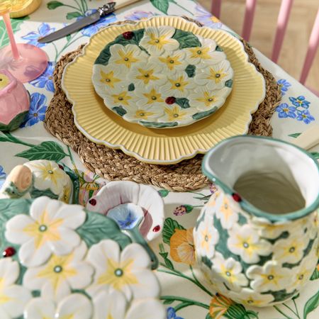 A dining table dressed in the Cosy Cottage trend with a floral-print tablecloth and a flower-embossed tableware