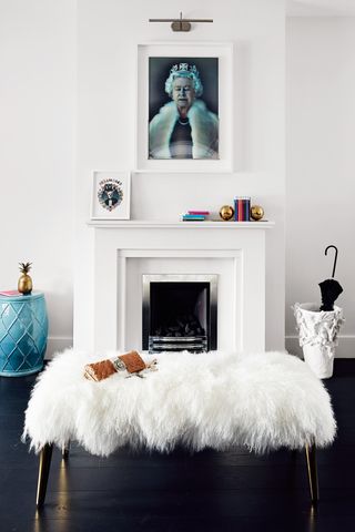 A living room with black flooring and a low stool with white fur