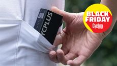 The Cycplus AS2 Pro being slipped into a cycling jersey pocket, showing its compact sizing with the Black Friday 2025 Cycling Weekly logo.