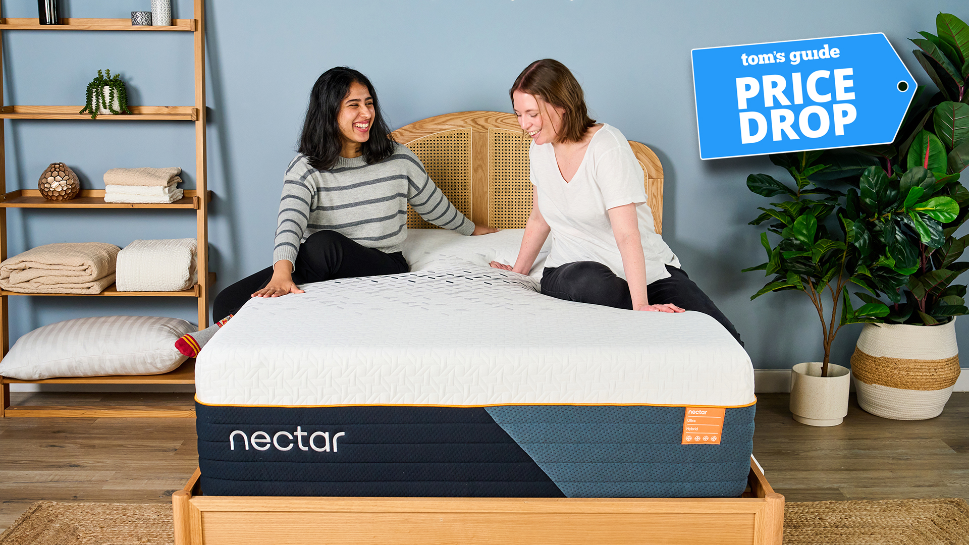 Two of our mattress testers sit on the Nectar Ultra Hybrid Mattress in a bedroom. In the top right is a Tom's Guide Price Drop deals graphic