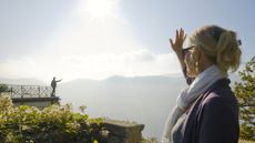 A man waves to a woman from a balcony above Lake Lugano, Italy.