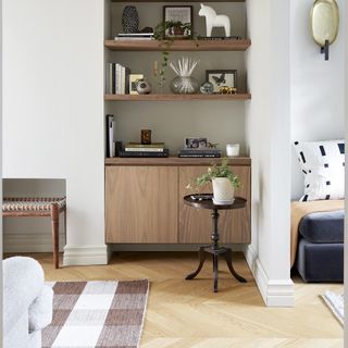 Living room with oak built in shelves, a vintage wood side table and white walls.