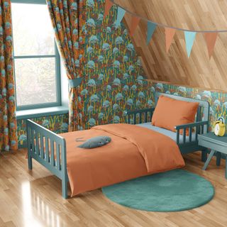 kids bedroom with patterned wallpaper and orange duvet