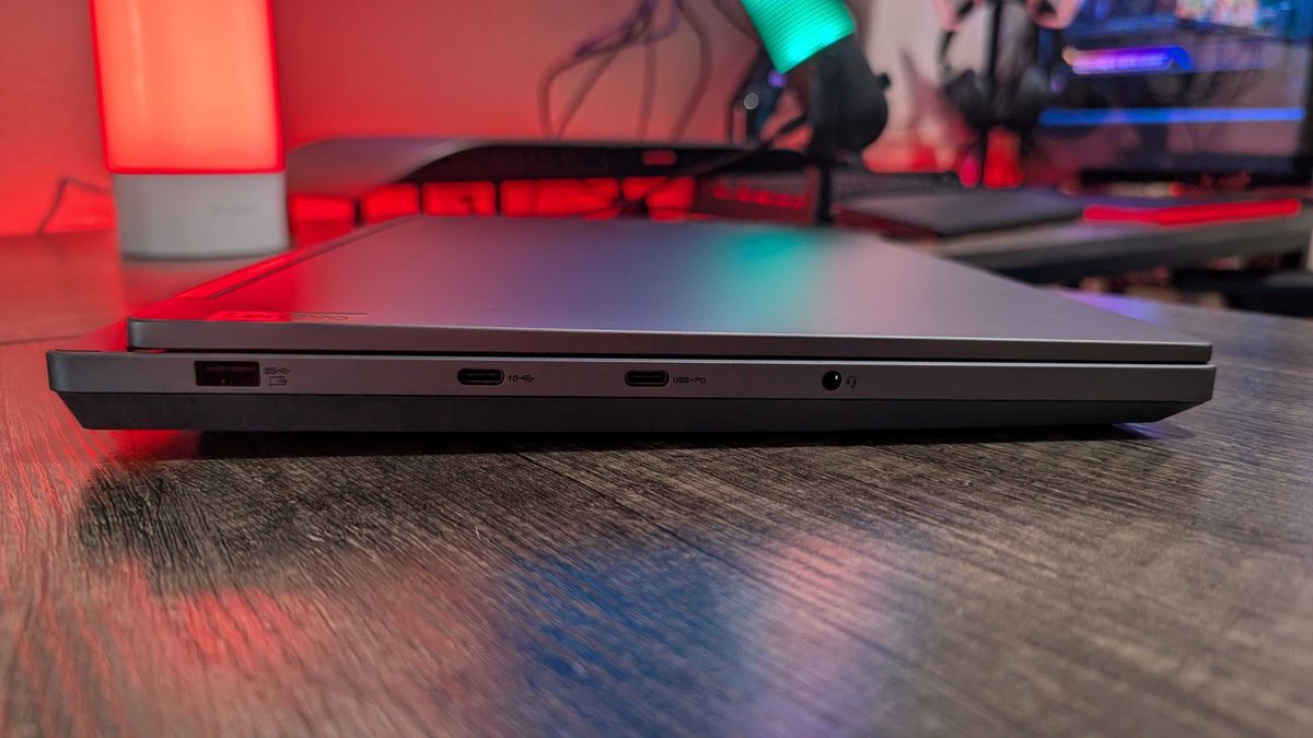 A Lenovo Legion 5i (Gen 9) gaming laptop on a desk with a red backlight, seen from the right to show the USB Type-A 3.2 Gen 1 (always on) port, the USB Type-C 3.2 Gen 2 port (with DisplayPort 1.4), the USB Type-C 3.2 Gen 2 port (with DisplayPort 1.4 and 140W Power Delivery), and the 3.5mm audio jack.