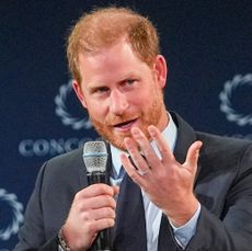 Prince Harry wearing a suit and speaking into a mic