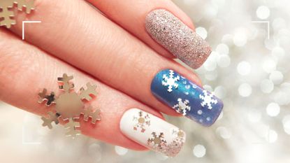 a woman&#039;s hands pictured with blue and white snowflake nail art