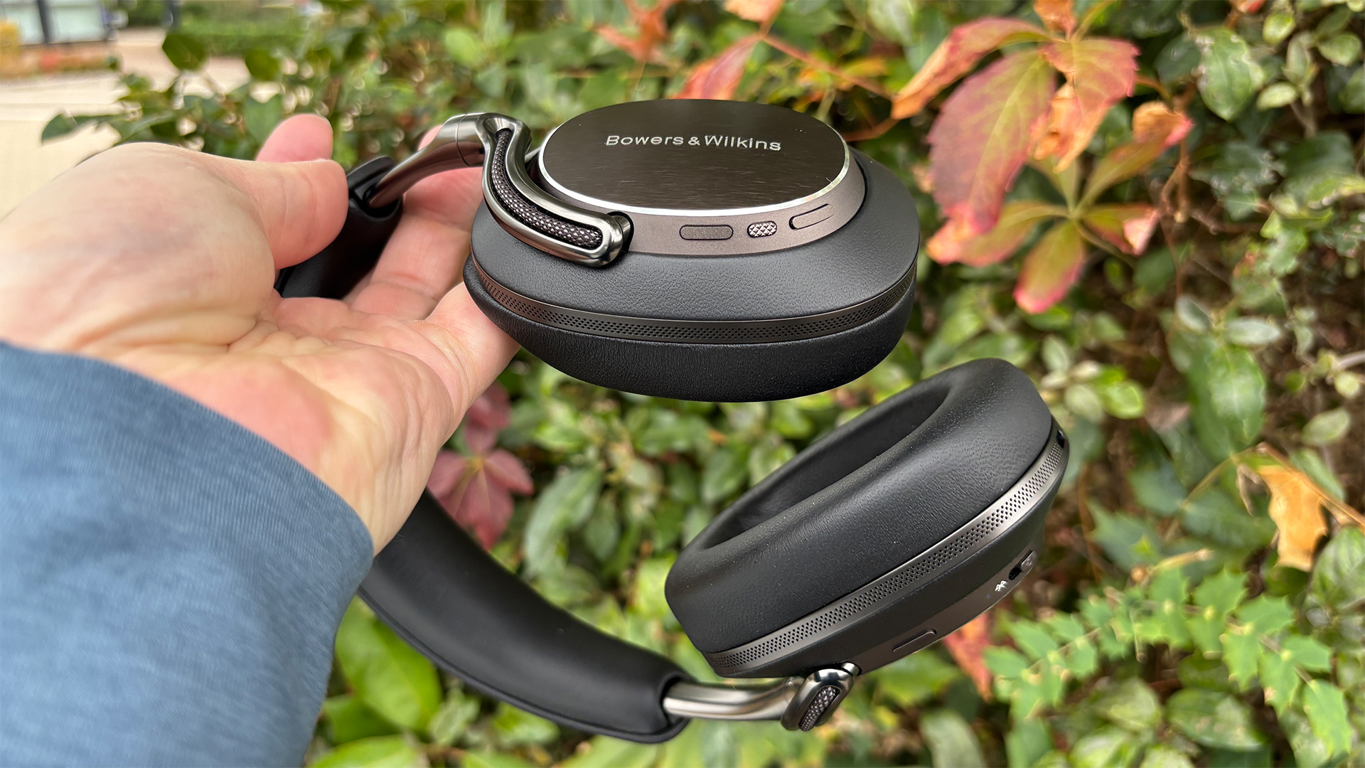 Bowers &amp;amp; Wilkins Px8 S2 wireless headphones held in hand in front of bush