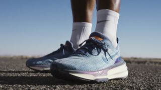 Man's feet wearing Nike Invincible 3 shoes standing on asphalt