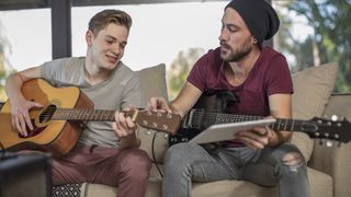 Boy with an acoustic guitar having a guitar lesson