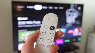 Chromecast with Google TV remote in front of TV