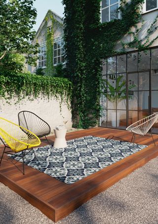 patterned blue and white outdoor rug on a decked patio with colourful string chairs