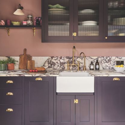 Burgundy painted kitchen with darker kitchen cupboards and a marble countertop