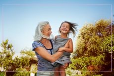 Grandmother holding smiling grandchild outside in the sunshine