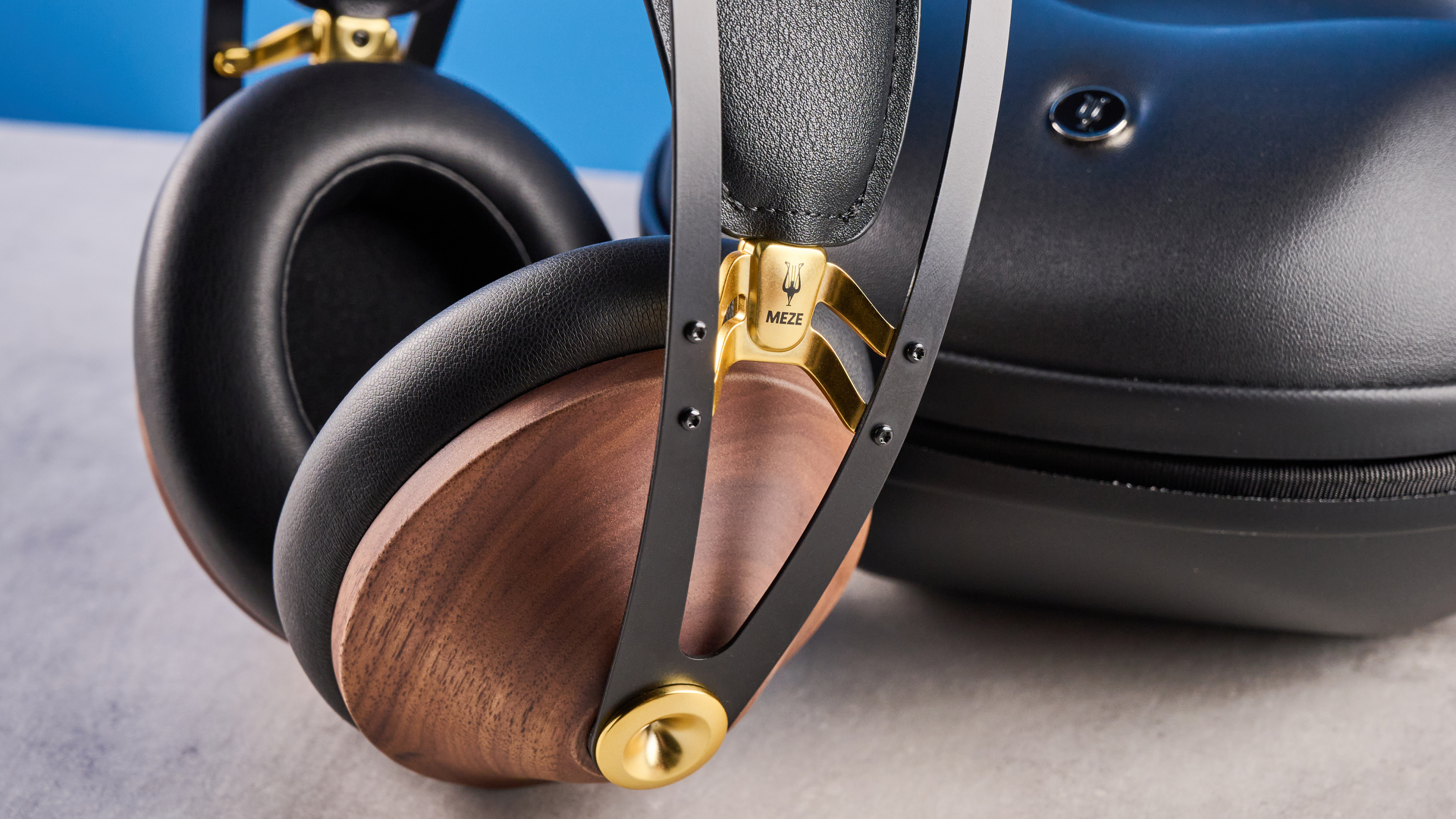 the meze 99 classics 2nd gen headphones with walnut finishes and gold touches against the blue tom&#039;s guide background