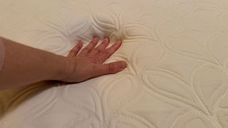Close-up of a hand pressing into the Cocoon by Sealy Chill mattress