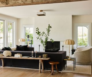 living room with white walls and dark sofa and wooden console table wooden beam