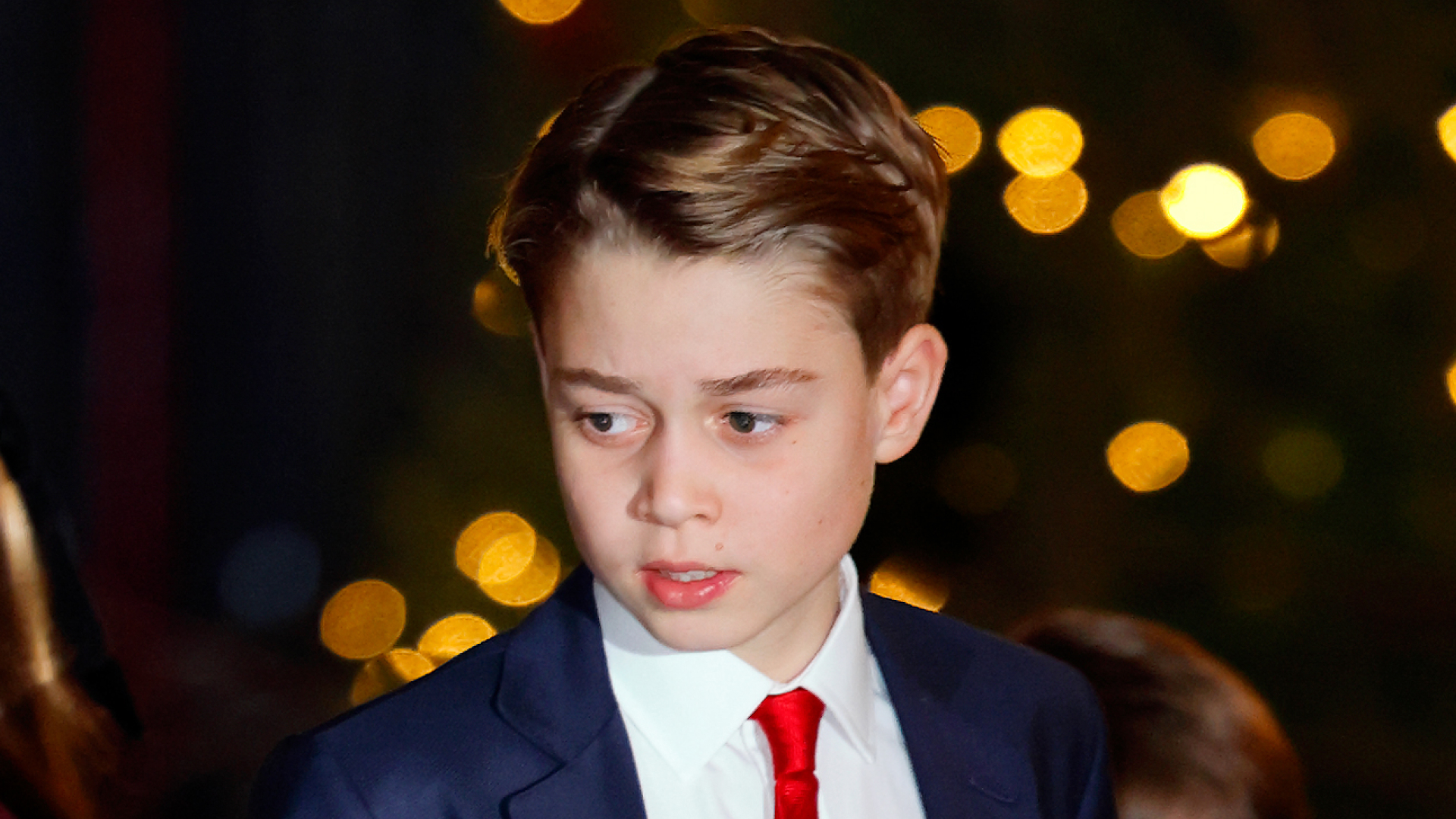 Prince George wearing a navy suit, white shirt, red tie
